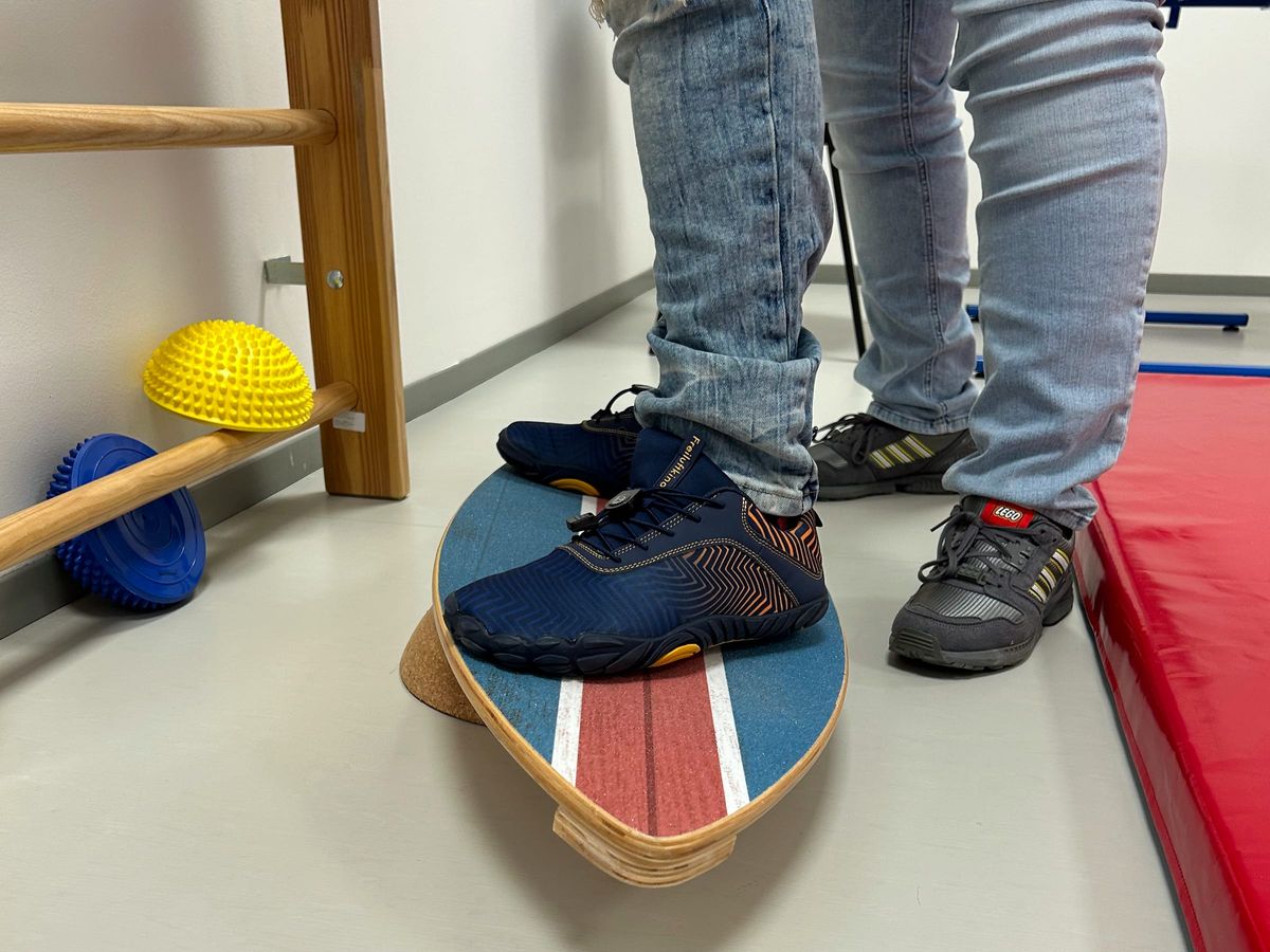Füße balancieren auf einem Balancebrett im Bewegungsraum