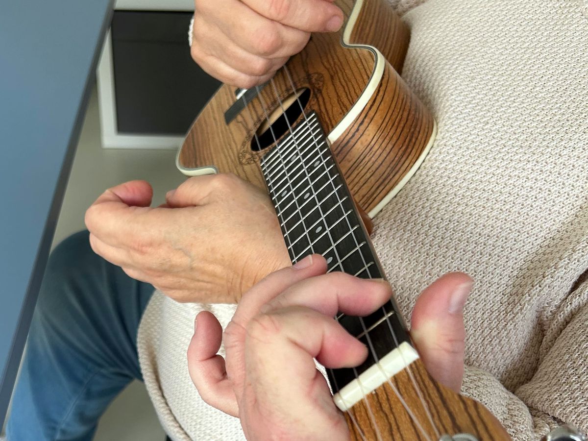 Ergotherapeutin führt die Hand am Griffbrett einer Ukulele