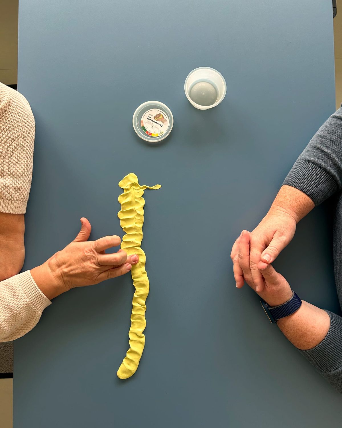 Zwei Händepaare arbeiten gemeinsam mit Therapieknete